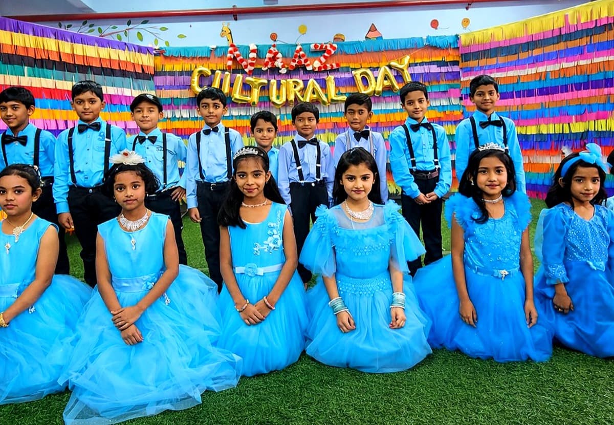 Naaz students dressed for Cultural Day in front of a bright ribbon backdrop